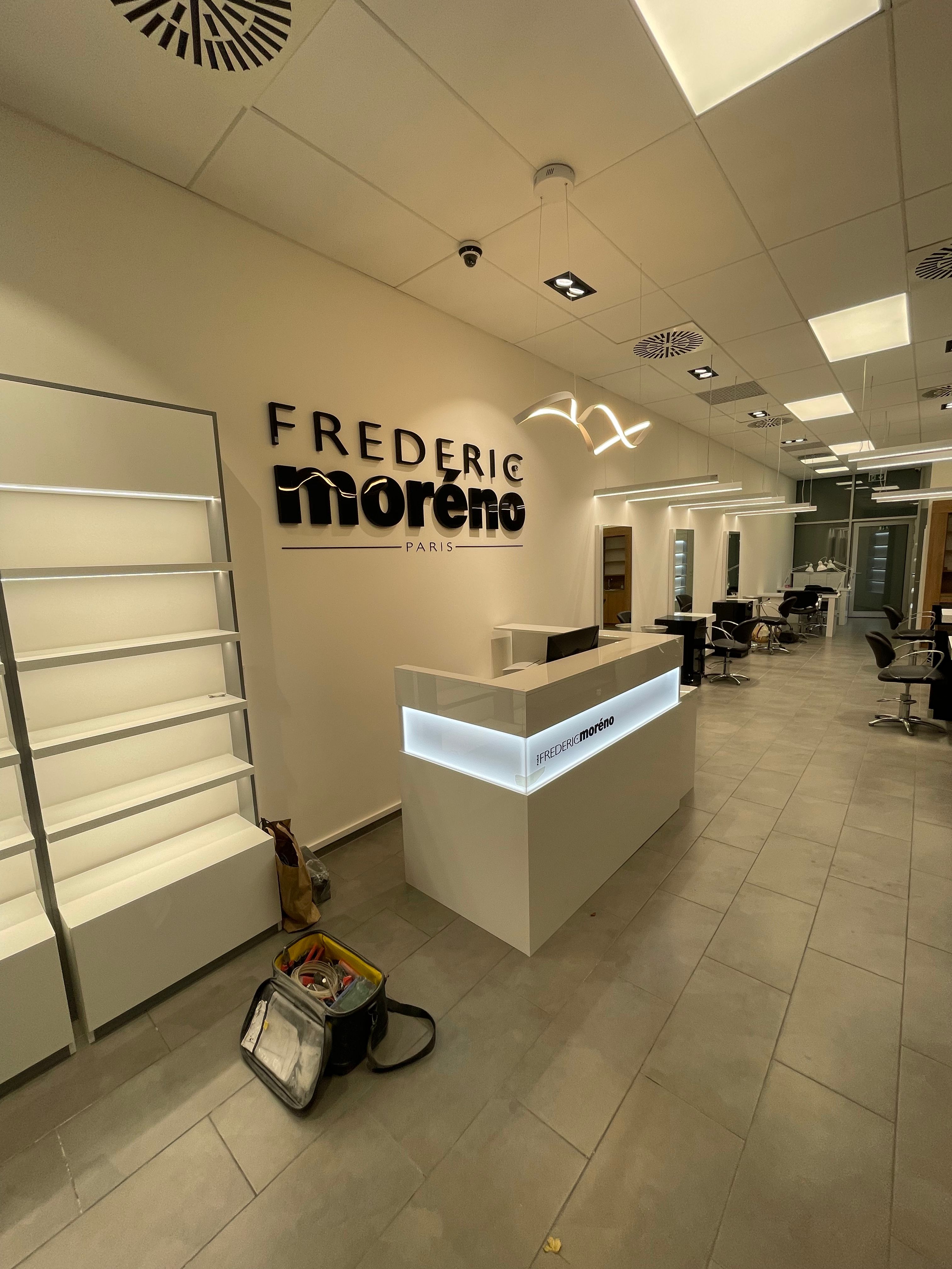 Recepčný priestor kaderníckeho salónu s logom a podsvieteným pultom